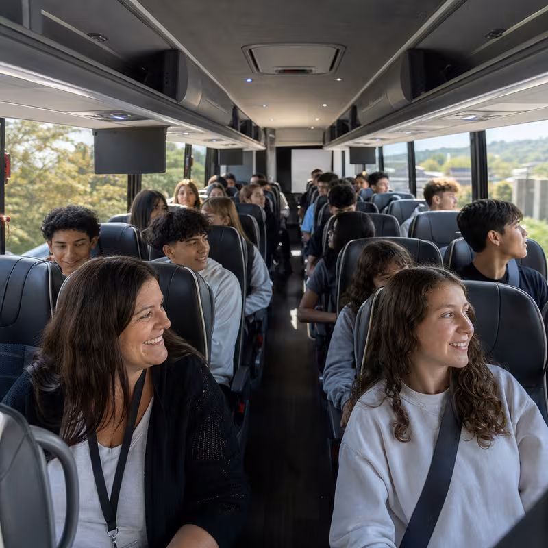 Group boarding a white charter bus for School Transportation transportation in Omaha