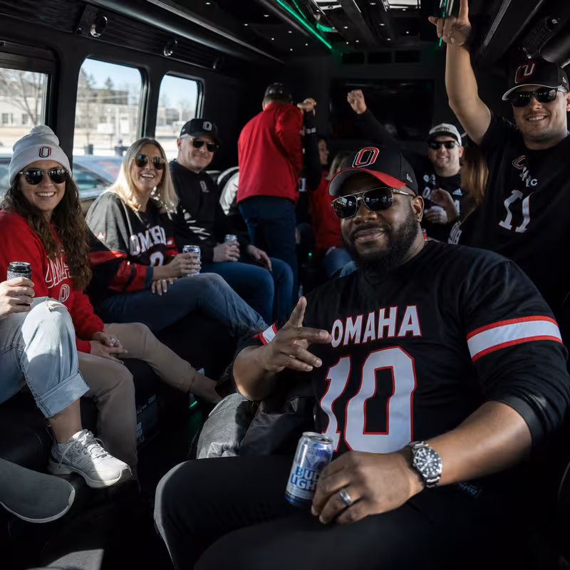 Group boarding a white charter bus for Sporting Event Transportation transportation in Omaha